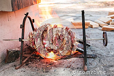 Fresh lamb meat on an open fire on a skewer for roasting-jack. daylight, wooden blocks are visible in the background Stock Photo