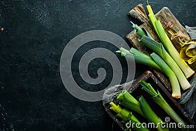 Fresh leeks in a wooden box on a black stone background. Top view. Stock Photo