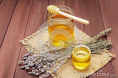 Fresh liquid honey in glass jars with a wooden honey dipper Stock Photo