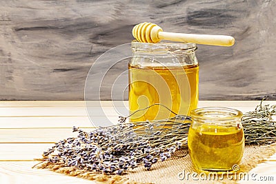 Fresh liquid honey in glass jars with a wooden honey dipper Stock Photo