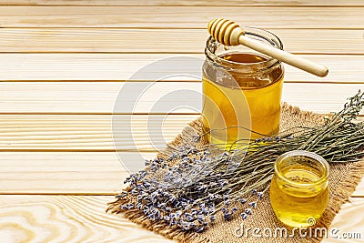 Fresh liquid honey in glass jars with a wooden honey dipper Stock Photo