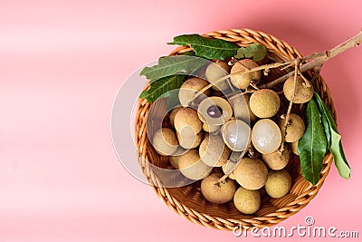 Fresh longan fruit in a basket on pink background Stock Photo