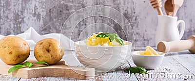 Fresh mashed potatoes and basil leaves in a bowl and whole potatoes on the table web banner Stock Photo