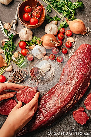 Fresh meat preparation and portioning.Whole uncut beef tenderloin.Raw meat seasoning.Hands portioning filet mignon steaks. Grass- Stock Photo