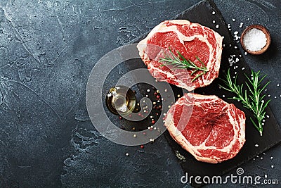 Fresh meat on slate black board top view. Raw beef steak and spices for cooking Stock Photo