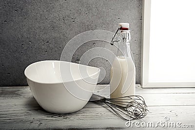 Fresh milk,cream bottle, bowl and wire whisk on window sill Stock Photo