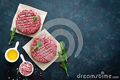 Fresh minced beef meat burgers with spices on dark background. Raw ground beef meat Stock Photo
