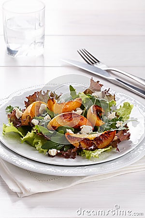 Fresh mixed salad on white. Lettuce and arugula leaves with grilled peach and blue cheese Stock Photo