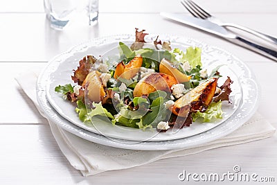 Fresh mixed salad on white. Lettuce and arugula leaves with grilled peach and blue cheese Stock Photo