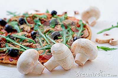 Fresh mushrooms on the white table with free copy space on the right side. Veggie pizza with vegetables, olives, rucola Stock Photo