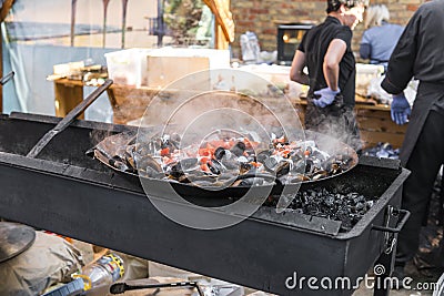 Fresh mussels at grill pan. Seafood barbecue outdoors. Picnic healthy food, mussels in shells. Plenty of mussel shells Editorial Stock Photo
