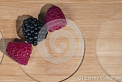 Fresh natural berries of raspberry and blueberry lie on a textured wooden board with circle cuts, top view Stock Photo