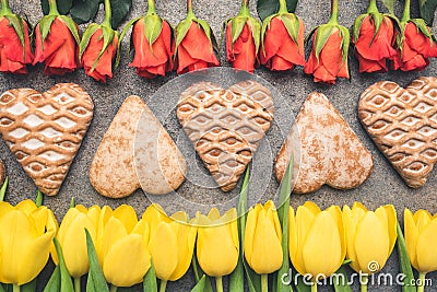 Flowers arranged on a climatic dark background. Heart-shaped gingerbreads arranged in the middle. Stock Photo