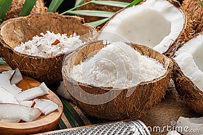 Fresh opened coconuts along with coconut slices, flakes and coconut leaves on a wooden table. Stock Photo