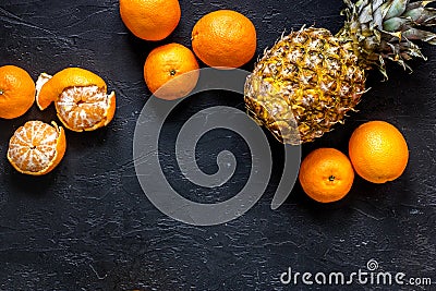 Fresh oranges, mandarins and pineapple on black table background top view copyspace Stock Photo