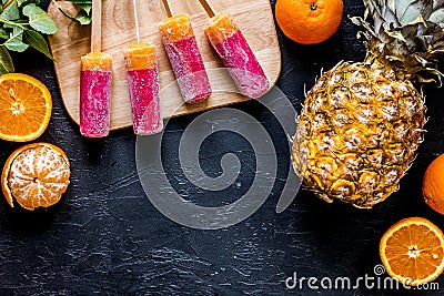 Fresh oranges, mandarins, pineapple and citrus ice cream on black table background top view copyspace Stock Photo