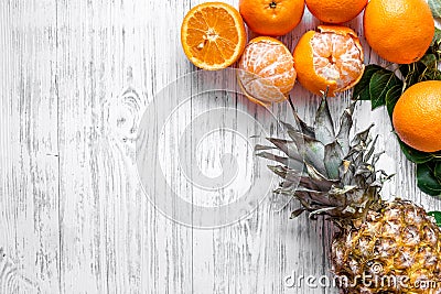 Fresh oranges, mandarins and pineapple on wooden background top view copyspace Stock Photo