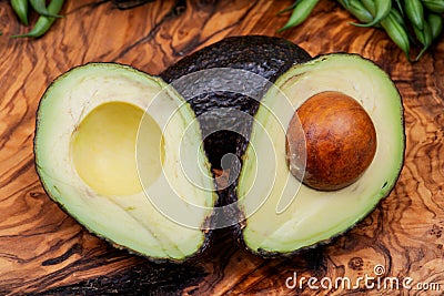 Fresh Organic Avocado cut in half arranged on olive wood. Persea americana in the Lauraceae family. Avocado Pear. Alligato Stock Photo