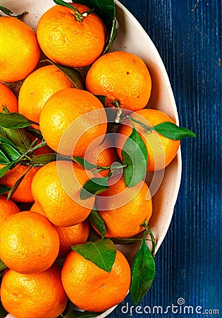 Fresh organic citrus mandarin oranges fruit tangerines, clementines with leaves in a light dish on a blue background Stock Photo