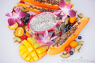 Fresh organic exotic fruits on white background. Ripe dargon fruit, papaya, kiwi, mango with kumquat, decorated with beautiful Stock Photo