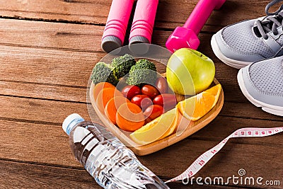 Fresh organic fruits and vegetables in heart plate wood and sports equipment Stock Photo