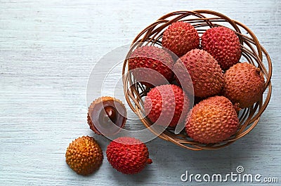 Fresh organic lychees in a basket on a light blue wooden background.Exotic tropical lichi fruits.Raw diet or vegan food concept. Stock Photo
