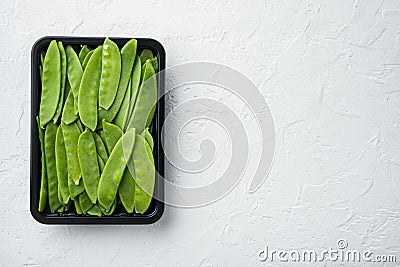Fresh organic mangetout, also known as sugar snap pea, in plastic container, on white stone background, top view flat lay , with Stock Photo