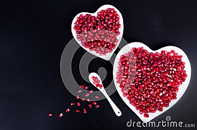 Fresh organic pomegranate seeds in white heart shaped bowl. Free space for your text. Stock Photo