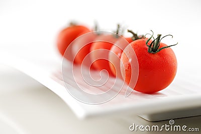 Fresh organic tomatoes on a white ceramic plate Stock Photo