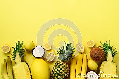 Fresh organic yellow fruits over sunny background. Monochrome concept with banana, coconut, pineapple, lemon, melon. Top Stock Photo