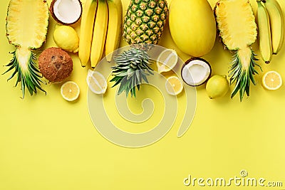 Fresh organic yellow fruits over sunny background. Monochrome concept with banana, coconut, pineapple, lemon, melon. Top Stock Photo