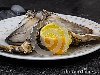 Fresh Oysters in plate, lemon, shells on marble. Delicacy super food, rich in antioxidants, vitamin, zinc Stock Photo