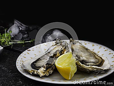 Fresh Oysters in plate, lemon, shells on marble. Delicacy super food, rich in antioxidants, vitamin, zinc Stock Photo