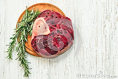 Fresh piece of meat large beef steak on the bone ossobuco with pepper, rosemary on the board. Stock Photo