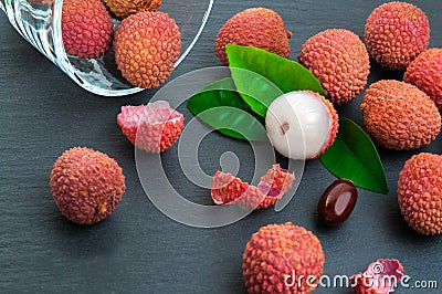 Fresh pile of lychees with leaves on black stone background Stock Photo