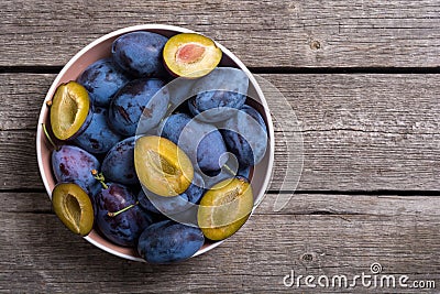 Fresh plums in bowl on wooden table Fruit background Stock Photo