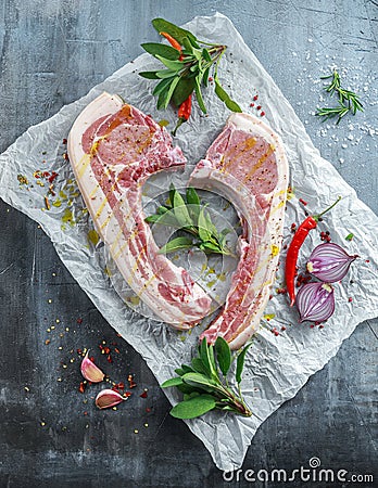 Fresh Pork middle cut ready to cook served with sage, red onion, chillies and red pepper drizzled with olive oil on Stock Photo