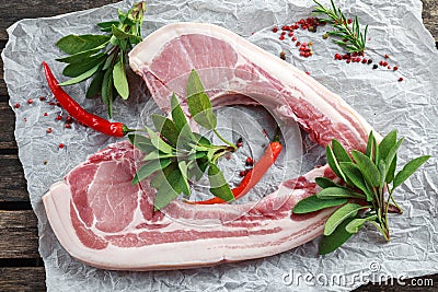 Fresh Pork middle cut ready to cook served with sage, red onion, chillies and red pepper drizzled with olive oil on Stock Photo