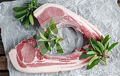 Fresh Pork middle cut ready to cook served with sage, red onion, chillies and red pepper drizzled with olive oil on Stock Photo