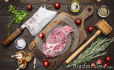 Fresh pork steak on a cutting board with rosemary, a hammer for beating the meat and ax for meat, seasoning herbs on wooden ru Stock Photo