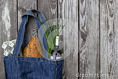 Fresh produce in blue denim market bag on wooden background, flat lay. Eco friendly reusable shopping bag for minimize waste, Stock Photo