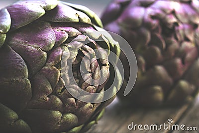 Fresh purple artichokes on dark rustic wooden background . Stock Photo