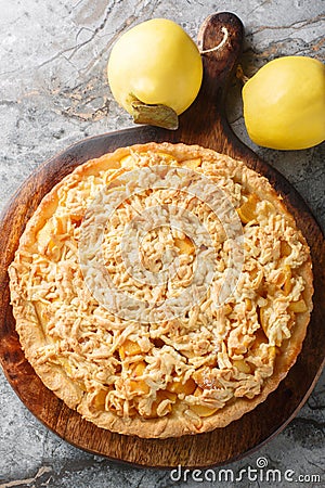 Fresh Quince crumble tart closeup on the wooden board. Vertical top view Stock Photo