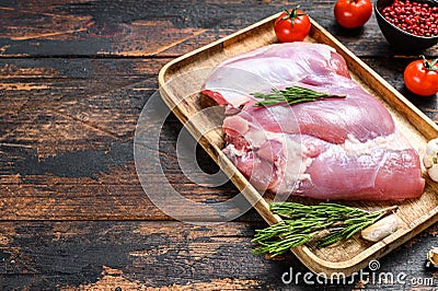Fresh raw boneless Turkey thigh fillet on a wooden tray. dark background. Top view. Copy space Stock Photo
