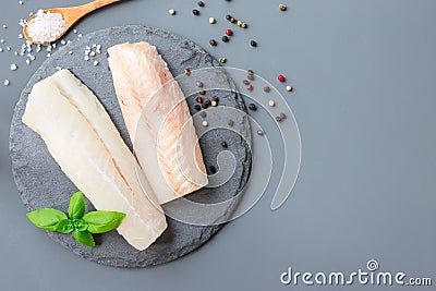 Fresh raw cod fillet with spices, pepper, salt, basil on stone p Stock Photo