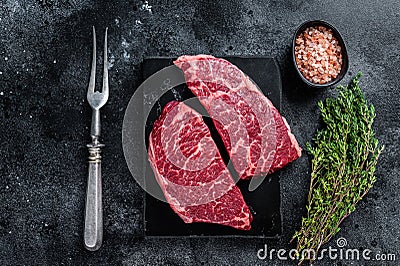 Fresh Raw Denver steak Marble beef meat with herbs. Black background. Top view Stock Photo