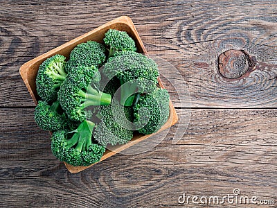 Fresh raw green broccoli in wooden bowl on wooden background, to Stock Photo