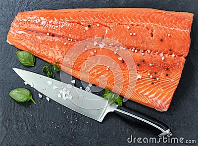 Fresh raw pacific wild king salmon on natural stone with spices and basil leaves Stock Photo