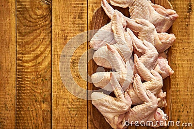 Fresh raw organic chicken wings on chopping board on wooden table. Stock Photo