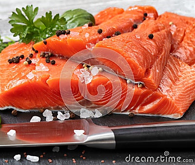 Fresh raw pacific wild king salmon fillets on natural stone with spices and basil leaves Stock Photo